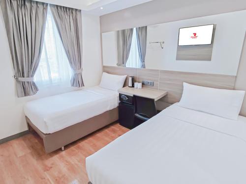 a hotel room with two beds and a desk at Red Planet Makati Amorsolo in Manila