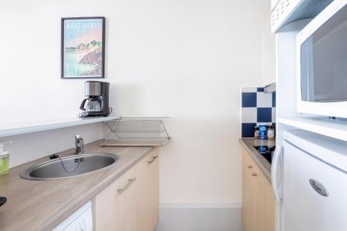a small kitchen with a sink and a microwave at La Cabine in Fouesnant