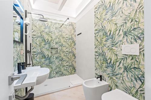 a bathroom with a white sink and a green leaf wallpaper at Dimora Storica Lucia in Ascea