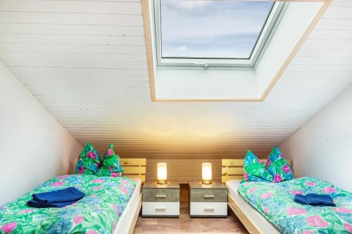 a attic bedroom with two beds and a window at Haus Erichsen in Perlesreut