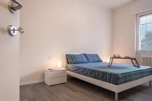 a white bedroom with a bed and a window at Maison Bibi Lago Maggiore in Laveno-Mombello