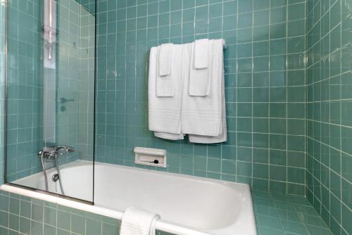 a green tiled bathroom with a bath tub and towels at Casa de Santo António Moledo in Moledo