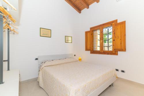 a white bedroom with a bed and a window at San Teodoro Villa Nina Costa Caddu in San Teodoro
