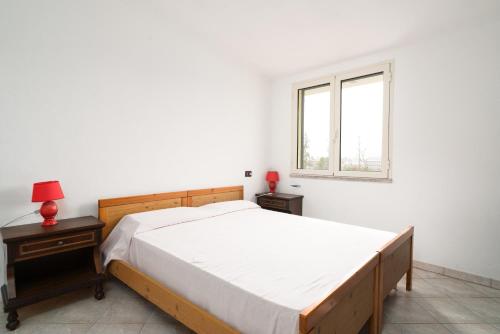 a white bedroom with a bed and a window at Casa nel centro di Budoni in Budoni