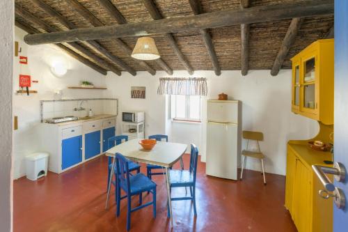 a kitchen with a table and some blue chairs at Herdade Vale de Gaios in Odemira