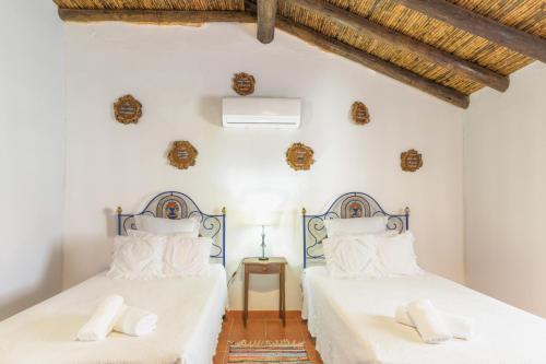 two beds in a bedroom with white walls and wooden floors at Herdade Vale de Gaios in Odemira