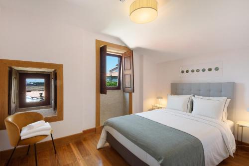 a bedroom with a large bed and a chair at Villa Casa do Outeiro in Guilhabreu