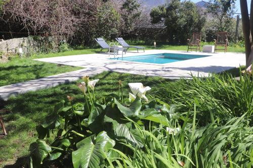 a garden with a pool with two chairs and flowers at Villa Casa do Outeiro in Guilhabreu