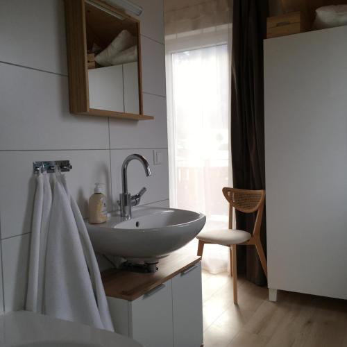 a bathroom with a white sink and a chair at Ferienhaus Seltschach 193 in Arnoldstein