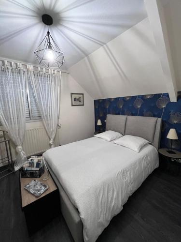 a bedroom with a large white bed with blue walls at Pause Tranquille - Chambres d'hôtes in Sablé-sur-Sarthe