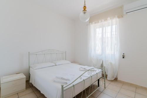 a white bedroom with a bed and a window at Casa Giselle a Otranto in Otranto