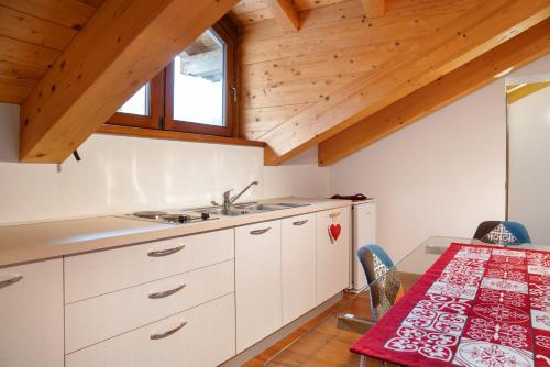 a kitchen with white cabinets and a wooden ceiling at Residence Chalet Provenzale in Acceglio