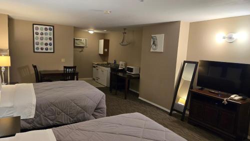 a hotel room with a bed and a flat screen tv at Red Coat Inn Motel in Fort Macleod