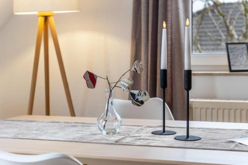 a glass vase sitting on a table with two candles at Haus Gertrud in Wiek auf Rügen