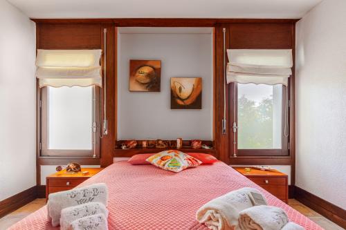 a bedroom with a pink bed with two windows at Sunset Troia Beach in Troia
