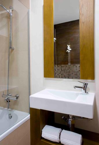 a bathroom with a white sink and a mirror at Hotel Parque das Laranjeiras in Vilamoura
