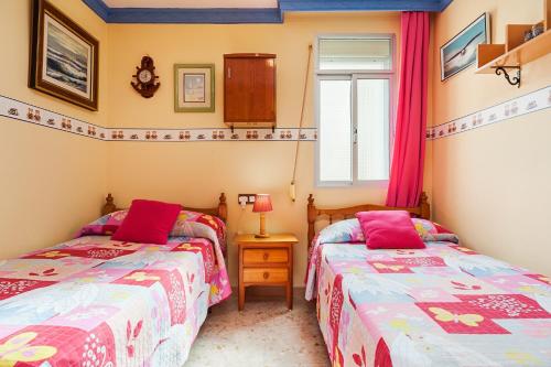 two twin beds in a room with a window at Apartamento Oliva in Barbate