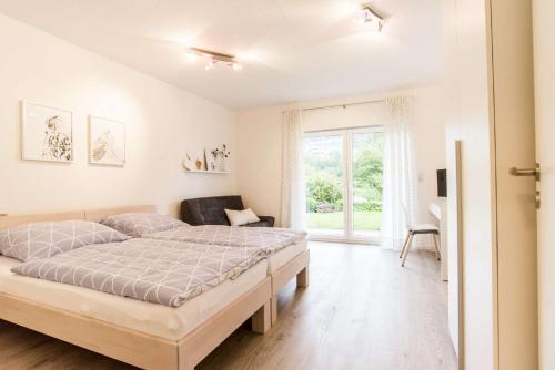 a white bedroom with a bed and a window at Ferienwohnung Am Holing in Bischoffen