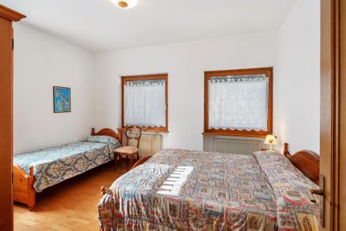 a bedroom with two beds and two windows at Residence Malibu Appartamento 3 in Falcade