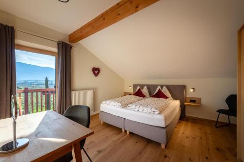 a bedroom with a bed and a desk and a balcony at Weinangerhof St Pauls in Missiano