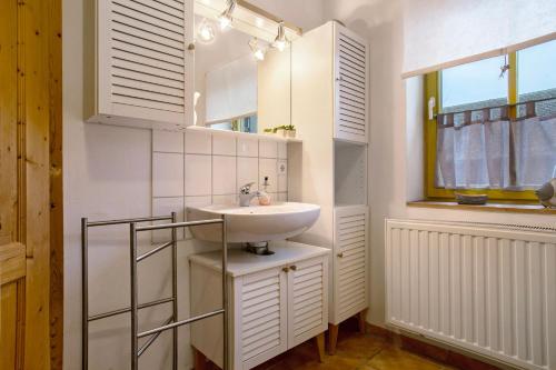 a white bathroom with a sink and a window at Ferienhaus Poggenkrug Halbsguth in Wolgast