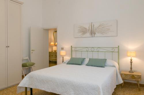 a bedroom with a white bed with two green pillows at Brezza Marina Apartment in San Vincenzo