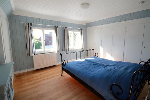 a bedroom with a bed with blue sheets and two windows at Villa Kunterbunt in Lindau