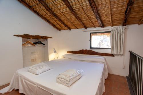 a bedroom with a white bed with two towels on it at Hora Hora in Orosei