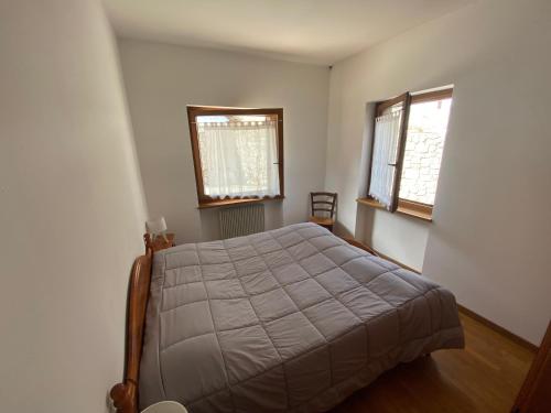 a bedroom with a bed and two windows at Residence Malibu Appartamento 2 in Falcade