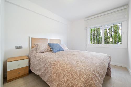a white bedroom with a bed and a window at Logroño in Salou