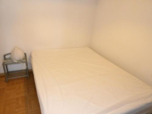 a small bedroom with a white bed in a room at studio la joue du loup in Le Dévoluy
