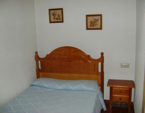 a bedroom with a wooden bed and a night stand at Casa Lopez San Martín in San Martín del Castañar