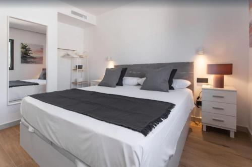 a white bedroom with a large bed with a black blanket at Villa Ona in Port de Soller