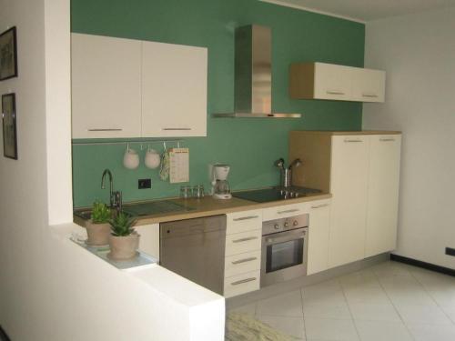 a kitchen with white cabinets and a green wall at Apartment CASA SPIAGGIA by Interhome in Castelletto di Brenzone