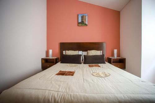 a bedroom with a large bed with an orange wall at Casa do Avô - Alojamento Sortelha in Sortelha