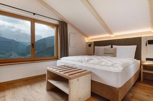 a bedroom with a large bed and a large window at Daunëihof in Selva di Val Gardena