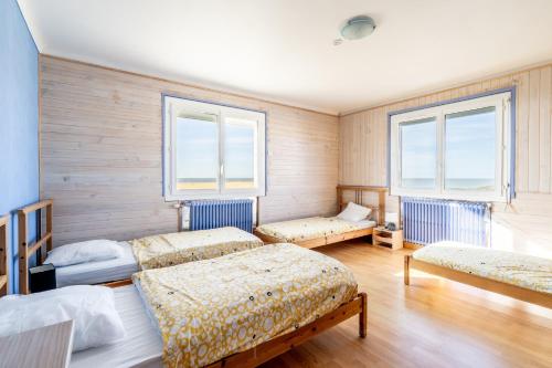 a bedroom with three beds and two windows at Logement vue mer à 50m de plage in Barbâtre