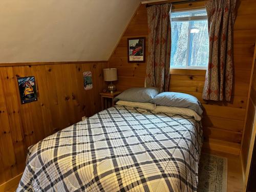 a bedroom with a bed in a wooden room at Red Sleigh Chalet - Campton in Campton