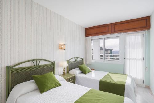 a hotel room with two beds and a window at Flamingo in Tavernes de Valldigna