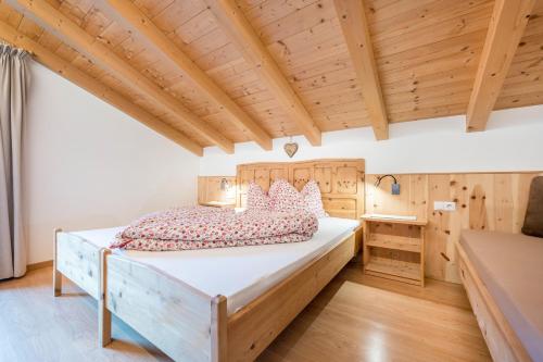a bedroom with a large bed and a wooden ceiling at Raffreiderhof Apt Zirbe in Luson