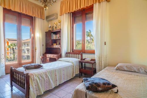 a bedroom with two beds and a room with windows at Il Comandante in Piedimonte Etneo
