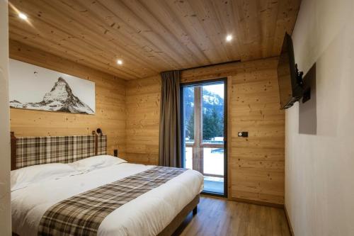 a bedroom with a bed and a large window at Chalet-Spa Le Cervin in Valloire