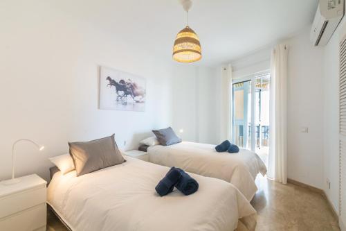 two beds in a room with white walls at Large Apartment Marbella del Mar in Marbella