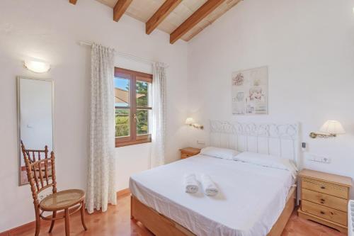 a bedroom with a bed and a chair and a window at Es Vinyo in Biniali