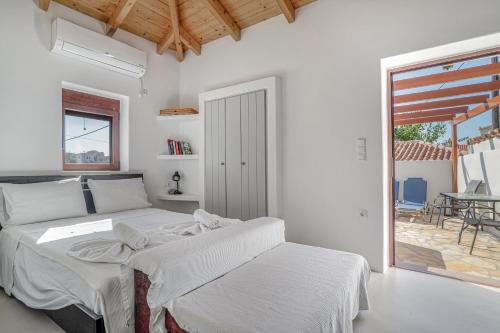 a white bedroom with two beds and a patio at Angel’s studio in Potamós