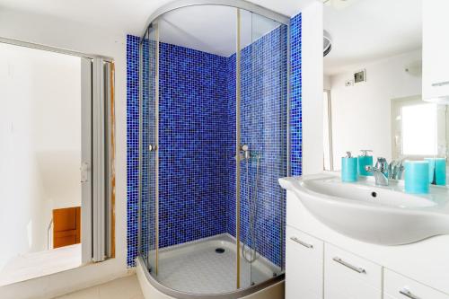 a bathroom with a sink and a shower with blue tiles at Elena Inn in Matino