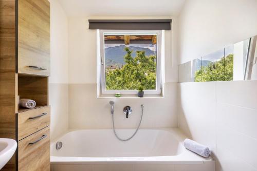 a white bath tub in a bathroom with a window at Angerblick Apartment in Appiano sulla Strada del Vino