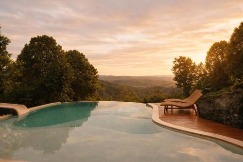 a swimming pool with a chair and a view at Bali Barn Village in Munduk