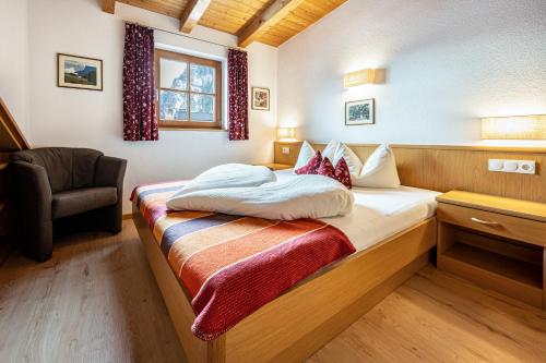 a bedroom with a bed with a chair and a window at App Sonnenschein - Duregger in Campo Tures