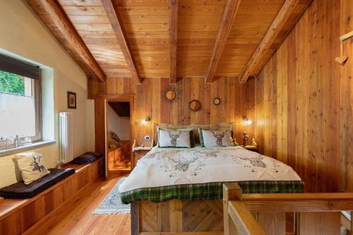 a bedroom with a bed in a room with wooden walls at La casa di Alice in Gignod